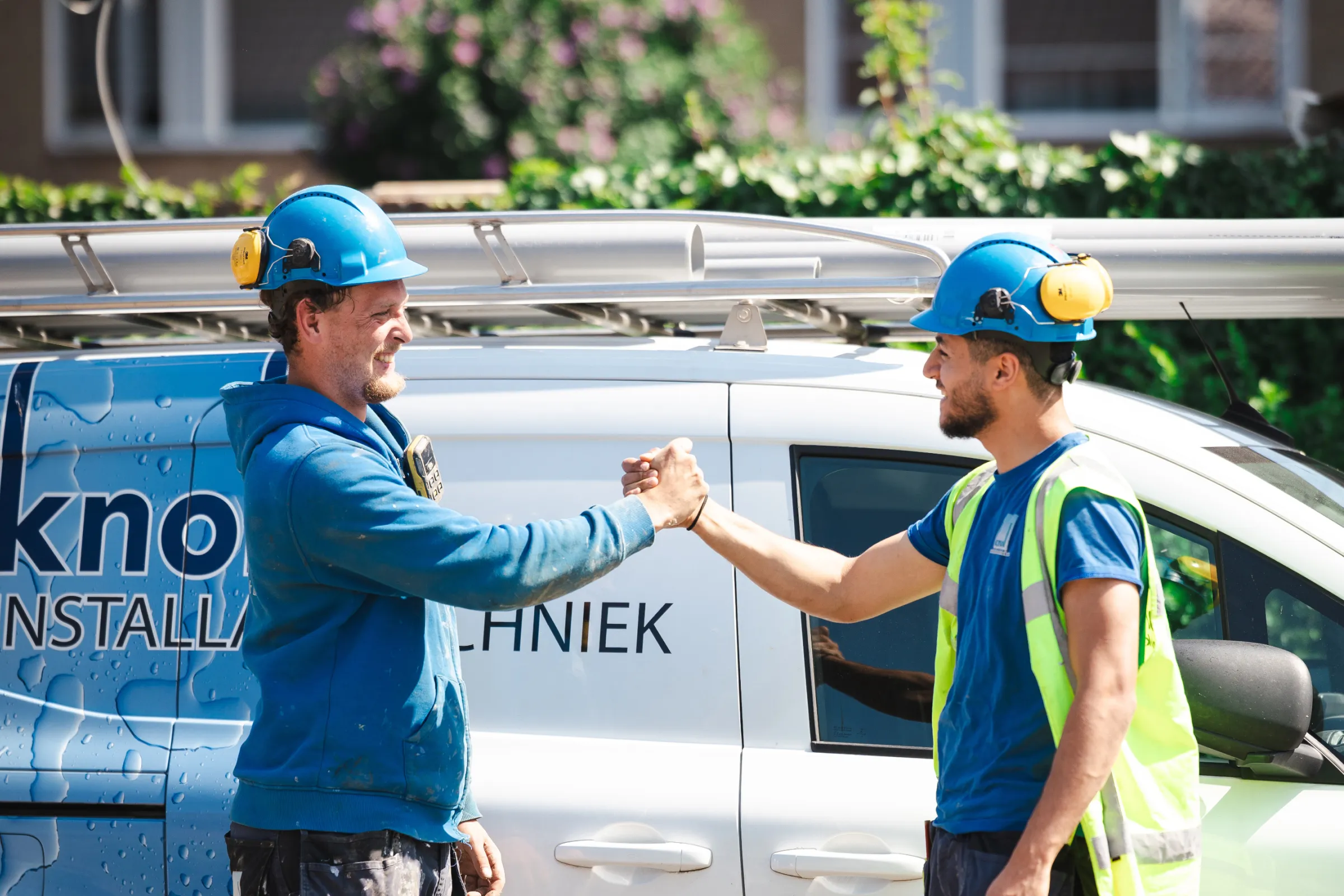 Twee collega’s begroeten elkaar bij een werkbus van Knol