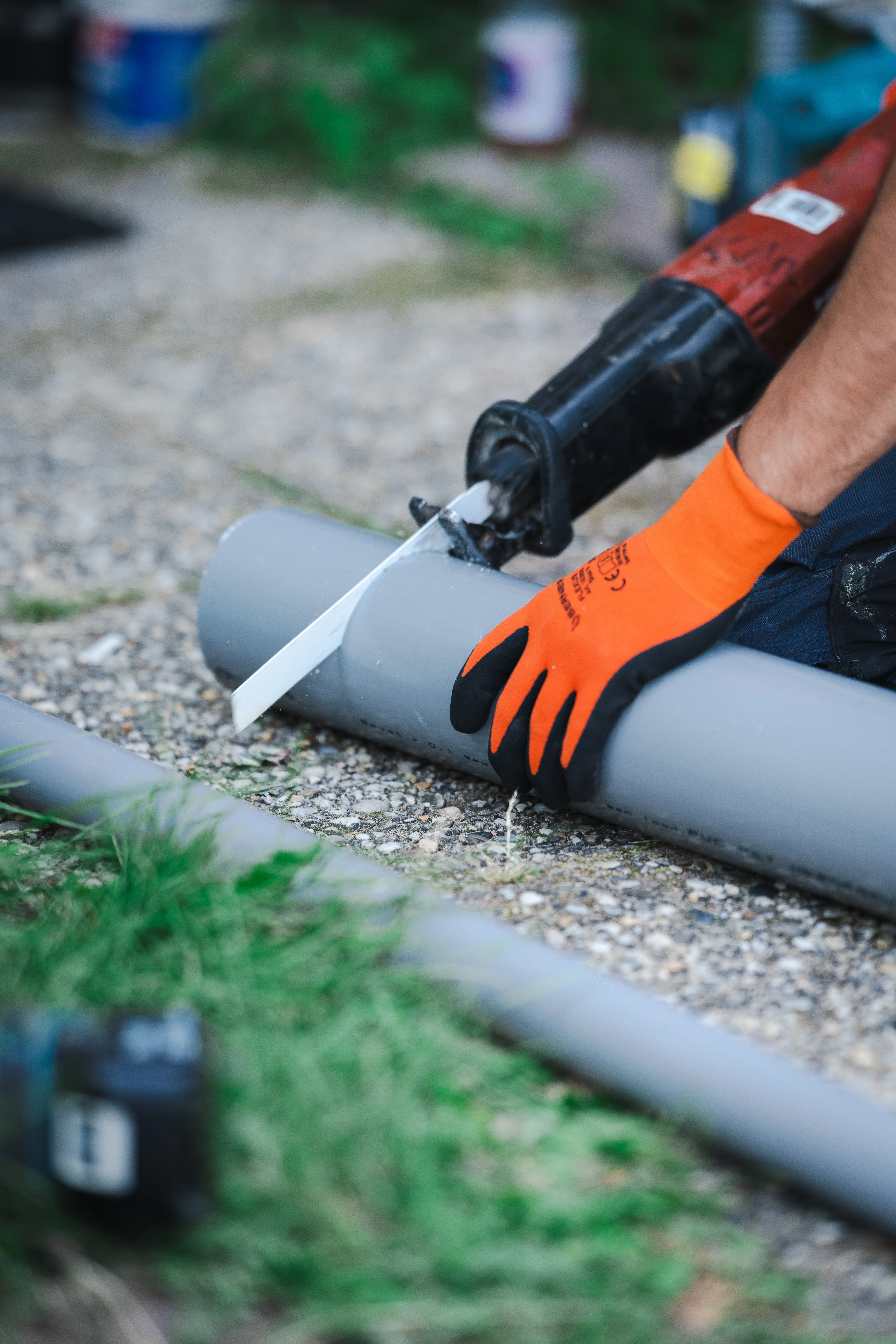 Installateur zaagt een grijze PVC-buis op maat